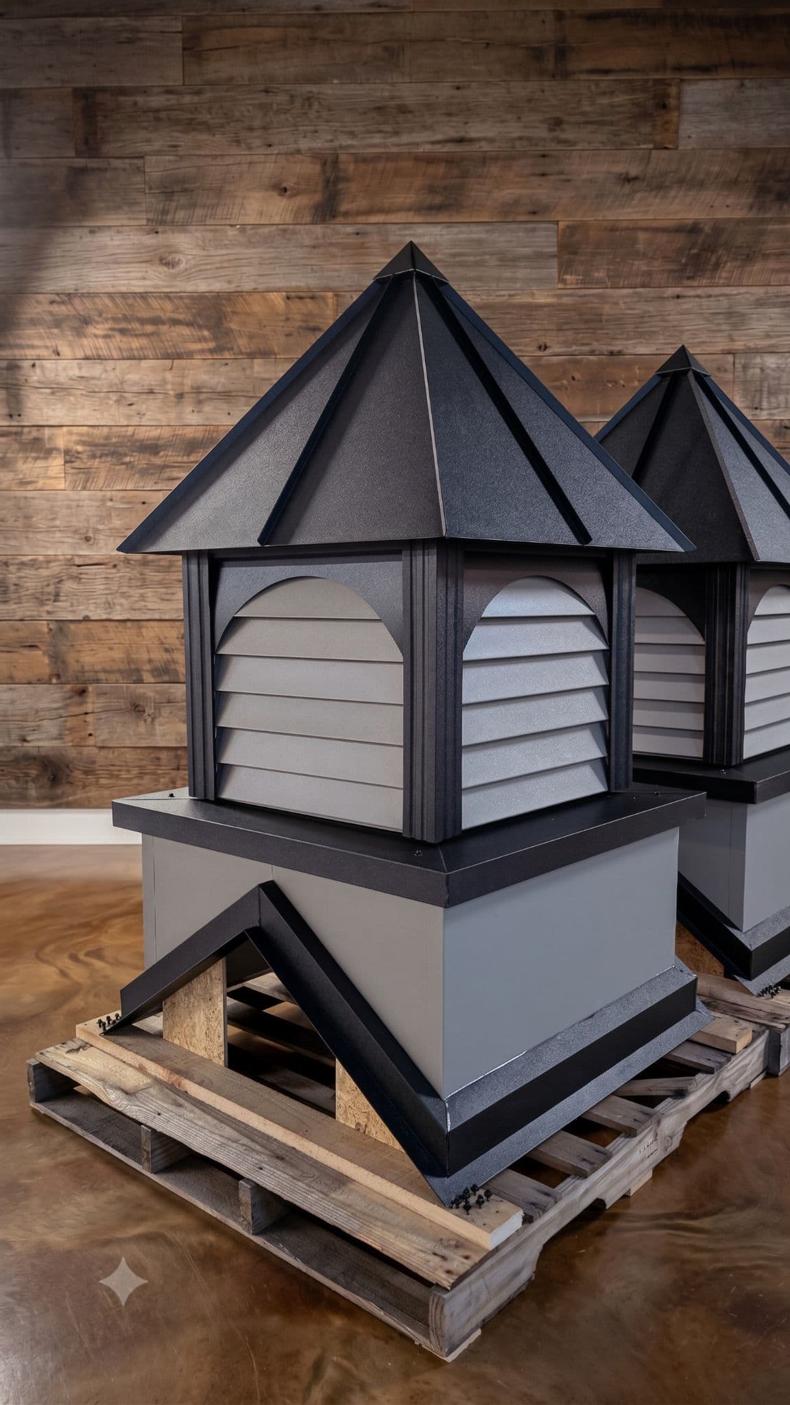 Close-up of a finished architectural louvered cupola showing metal roof ribs, louvers, trim, and pitch-cut base