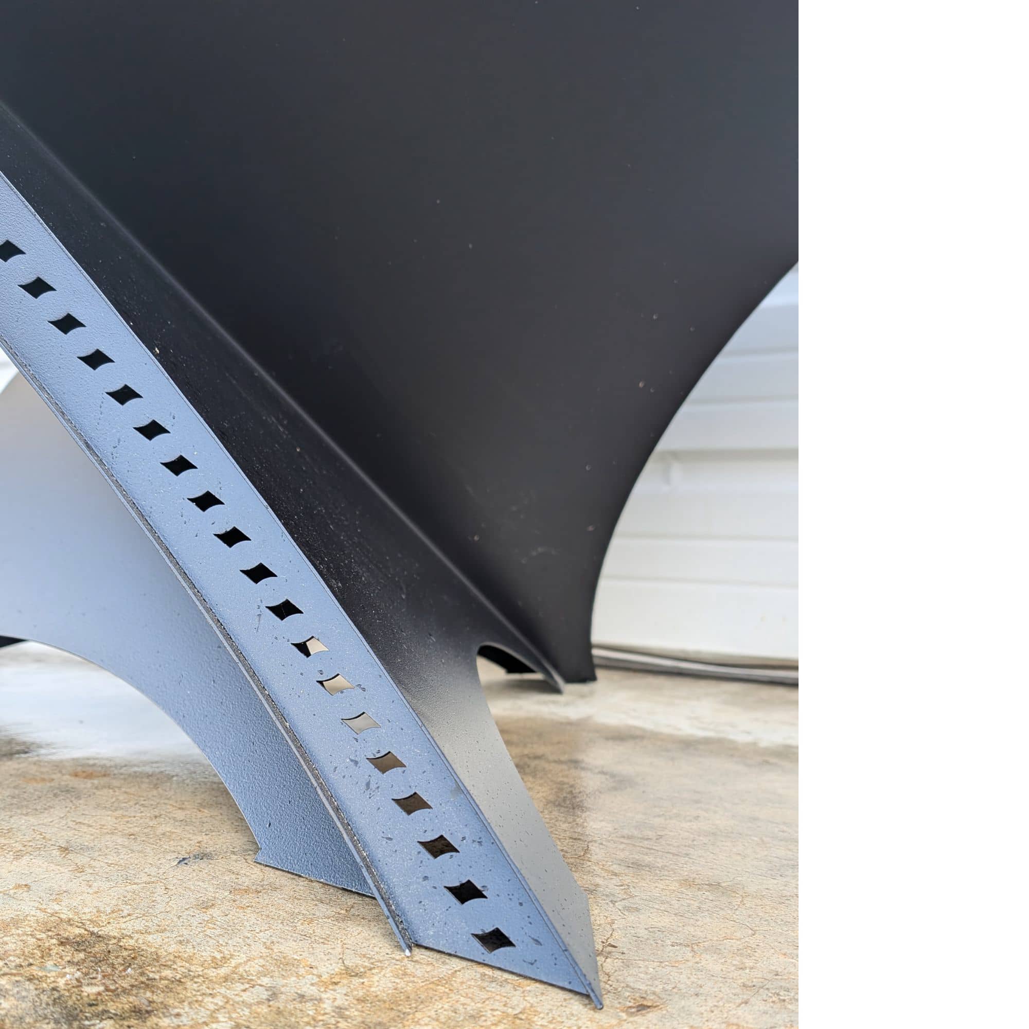 Close-up of ventilation slots along the lower edge of a triangular fire pit